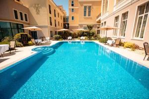 a large blue swimming pool with chairs and umbrellas at Hotel Tresor Le Palais in Timişoara
