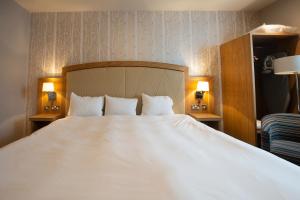 a large white bed in a hotel room at Sandford House Hotel Wetherspoon in Huntingdon