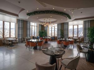- une salle à manger avec des tables, des chaises et des fenêtres dans l'établissement Rixos Krasnaya Polyana Sochi, à Estosadok