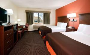 a hotel room with two beds and a flat screen tv at AmericInn by Wyndham Manitowoc in Manitowoc