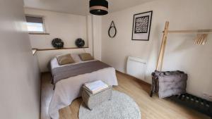 een slaapkamer met een bed en een stoel bij Maison L'Atelier des Salines in Lons-le-Saunier