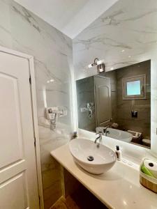 a white bathroom with a sink and a tub at Lido Sofia Apartments in Agios Gordios