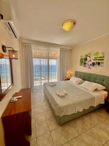 a bedroom with a large bed with a view of the ocean at Lido Sofia Apartments in Agios Gordios