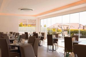 un ristorante con tavoli, sedie e ampie finestre di Cilento Holiday Village a Montecorice
