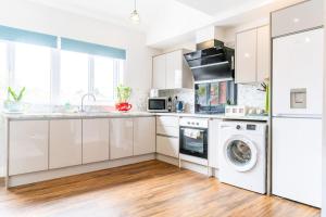 een keuken met witte kasten en een wasmachine en droger bij Moseley Haven 2 - Bed Luxury in Birmingham