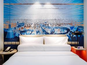 ibis Styles Manila Araneta City في مانيلا: غرفة نوم بسرير وجدار ازرق وابيض