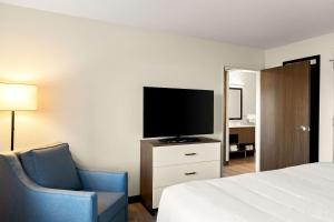 um quarto de hotel com uma cama, uma televisão e uma cadeira em Everhome Suites Nampa Boise em Nampa