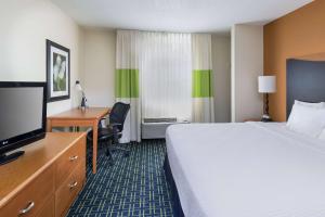 a hotel room with a bed and a desk and a television at AmericInn by Wyndham Topeka in Topeka