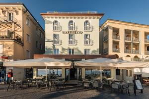 a restaurant with tables and umbrellas in front of a building at Hotel Giardinetto in Garda