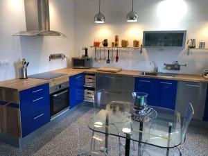 a kitchen with blue cabinets and a glass table at L 'Air Yaudet in Becléguer