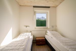 two beds in a room with a window at Hoogelandt 90A in De Koog