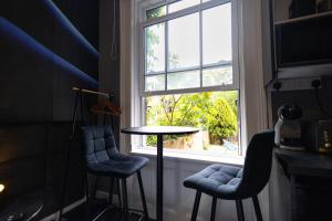 einen Tisch und zwei Stühle in einem Zimmer mit Fenster in der Unterkunft Elegant 1BR Flat l Jacuzzi l Prime London Location in London