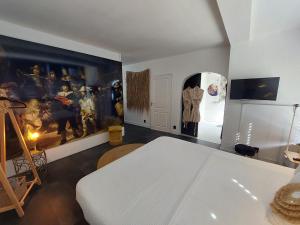 a room with a white bed and a painting on the wall at rembrandtsbeachsuite in Zandvoort
