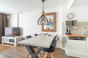 eine Küche und ein Esszimmer mit einem Tisch und Stühlen in der Unterkunft Appartementencomplex Juliana 72 in De Koog