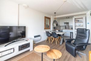 ein Wohnzimmer mit einem TV, einem Tisch und Stühlen in der Unterkunft Appartementencomplex Juliana 72 in De Koog