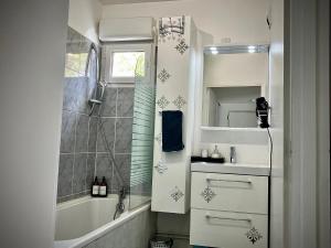 La salle de bains est pourvue d'une baignoire, d'un lavabo et d'une douche. dans l'établissement Snowqueen Hotel Apartment Paris-Disney, à Chelles