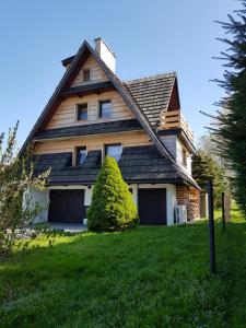 a house with a gambrel roof on a green lawn at Dom Górski Klimat-Willa 160 m2 z wewnętrzną sauną fińską in Zakopane