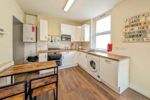 cocina con armarios blancos, lavadora y secadora en Town Centre House for 6 Guests, en Bournemouth