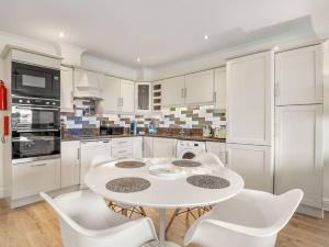 een witte keuken met een witte tafel en stoelen bij 419 Stunning Sea View Clifden Apartment in Clifden
