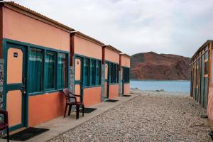 Lukung的住宿－Wanderlust Cottage Pangong Lake, Lukung,，坐在水边建筑物外的椅子