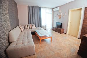 uma sala de estar com um sofá e uma televisão em Хотел и Вили Марая em Tsarevo