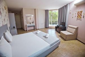 - une chambre avec un grand lit blanc et une chaise dans l'établissement Хотел и Вили Марая, à Tsarévo