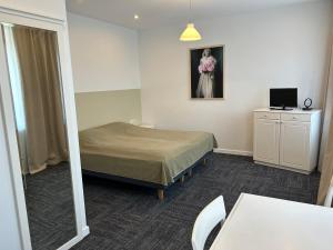 Kleines Zimmer mit einem Bett und einem TV in der Unterkunft Seven Sisters Apartments in Liepāja