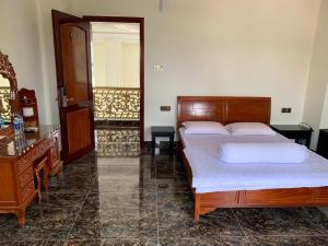 Schlafzimmer mit einem Bett, einer Kommode und einem Spiegel in der Unterkunft HOÀNG GIA BẠC LIÊU in Bạc Liêu