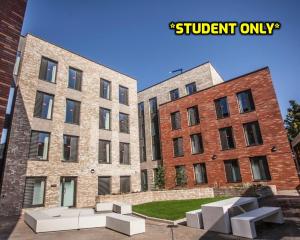 dos edificios de ladrillo con bancos blancos delante de ellos en Student Only Zeni Ensuite Rooms, Colchester en Colchester