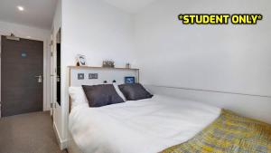 um quarto com uma cama com lençóis brancos e almofadas em Student Only Zeni Ensuite Rooms, Colchester em Colchester