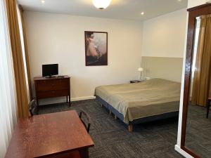 een hotelkamer met een bed, een tafel en een bureau bij Seven Sisters Apartments in Liepāja