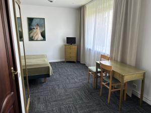 een kamer met een bed, een bureau en een tafel bij Seven Sisters Apartments in Liepāja