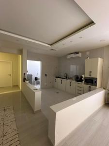 a large kitchen with white cabinets and a large window at فيلا دورين ومنطقة مخصصة للقهوة in Buraydah