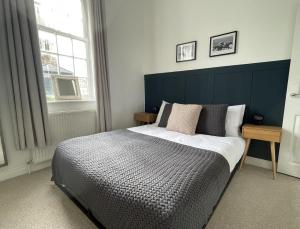 a bedroom with a bed with a blue headboard and a window at Apartment 3 St Georges in Cheltenham
