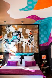 a bedroom with a bed with a wall covered in graffiti at Boutique Hôtel des Beaux Arts in Toulouse