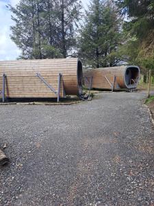 dos grandes barriles de madera sentados a un lado de una carretera en Celtic Minor Pods en Ystalyfera