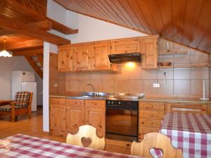 uma cozinha com armários de madeira, um lavatório e uma mesa em Amazing Apartment in Cavalese with Shared Terrace em Cavalese