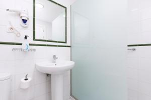 a white bathroom with a sink and a mirror at Apartamentos Erika - Adults Only in Corralejo