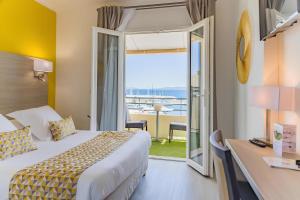 a hotel room with a bed and a view of the ocean at Le Rabelais in Le Lavandou