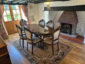 a dining room with a table and a fireplace at Beautiful Thatched Cottage with heated outdoor pool, Great for families & Dog Friendly! in Bosham