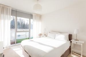 a white bedroom with a large bed and a large window at Modern Chiswick Apartment in London