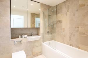 a bathroom with a tub and a sink and a mirror at Modern Chiswick Apartment in London