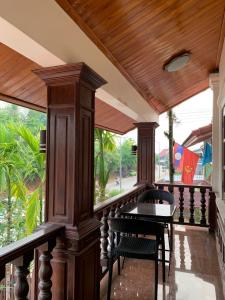 una veranda in legno con tavolo e sedie. di Heuang Paseuth Hotel 香帕赛酒店 a Luang Prabang