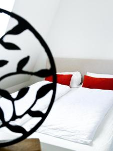 uma cama com lençóis brancos e almofadas vermelhas em Apartman Spaß em Šabac