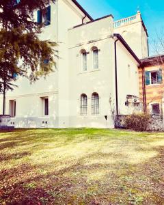 an old white house with a grass yard at Villa Ca' Damiani Rooms & Apartments in Caneva