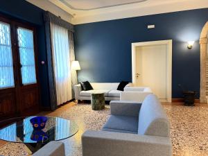 a living room with blue walls and couches and a table at Villa Ca' Damiani Rooms & Apartments in Caneva