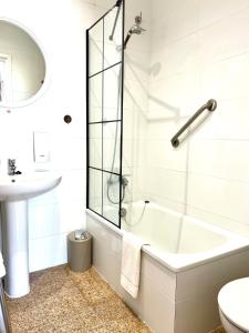 een witte badkamer met een bad en een wastafel bij Escondite central con terraza compartida en la azotea y cocina compartida in Roses