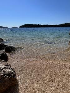 a beach with rocks and water and trees in the background at Inevig Holiday home in Rogoznica