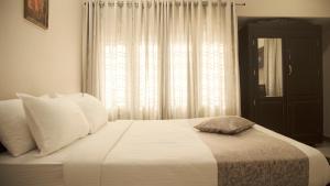 een slaapkamer met een wit bed en een raam bij Nambiars Premium Heritage Hotel in Cochin