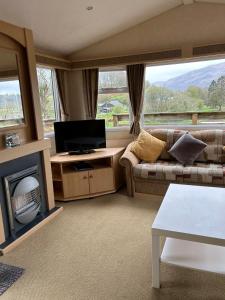 a living room with a couch and a tv at Curacao Caravans in Taynuilt